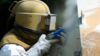 persoon in beschermende kleding bezig met corrosiebescherming| DID-online.nl